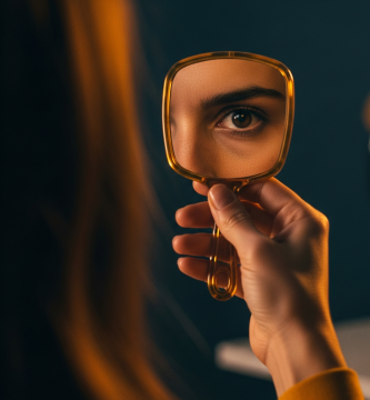 Primer plano cinematográfico del ojo de una mujer española reflejado en un espejo de mano ámbar, simbolizando el narcisismo.