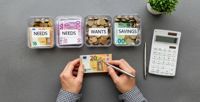 Manos organizando euros en tres frascos etiquetados '900€ Necesidades', '540€ Deseos', '360€ Ahorro'.