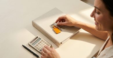 Llaves de casa y documento de seguro de hogar sobre mesa crema con calculadora