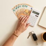 Fondo de emergencia en euros con libreta de notas, calculadora y llaves sobre fondo crema