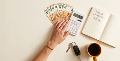 Fondo de emergencia en euros con libreta de notas, calculadora y llaves sobre fondo crema